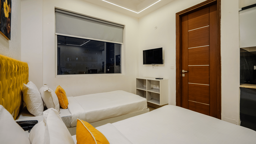 Bedroom of Lime Tree Luxury Studio featuring a wall mounted television, a shelving unit, and cushions.