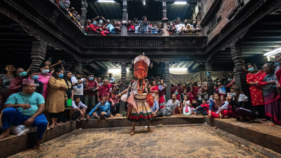 Spectators gathering on multiple wooden tiers of a historic building to watch a masked Lakhey dance in Bhaktapur, Nepal.