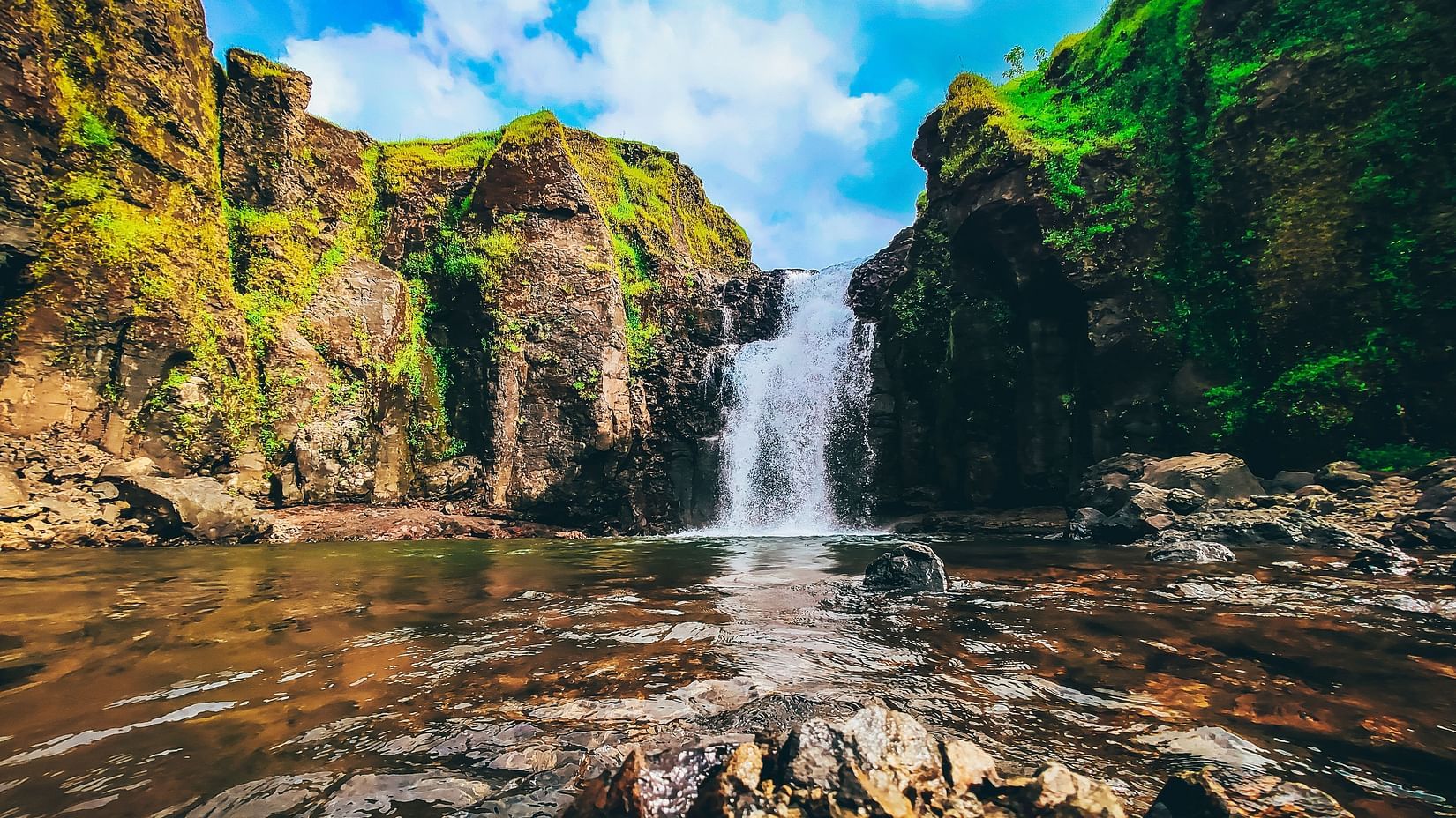 view of a waterfall amidst hills