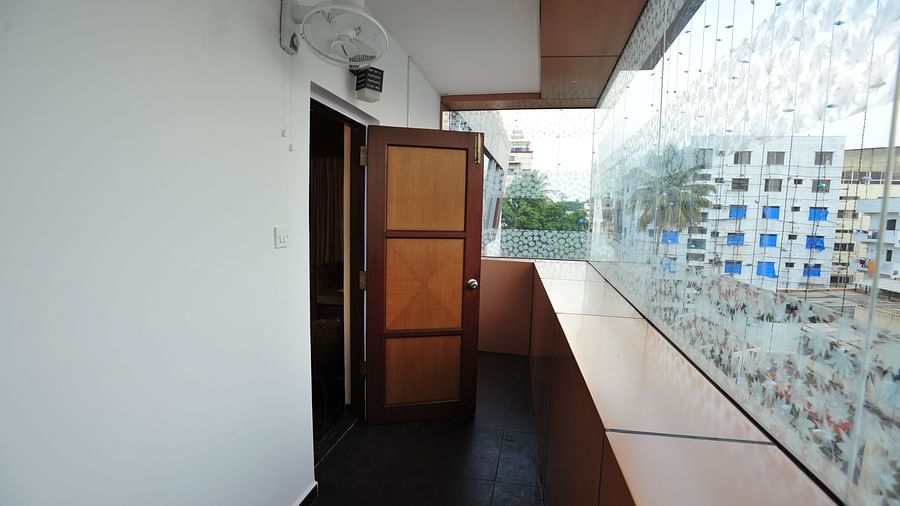 A family room's balcony with large glass windows showcasing the outer view at Hotel Dr. Rajkumar International