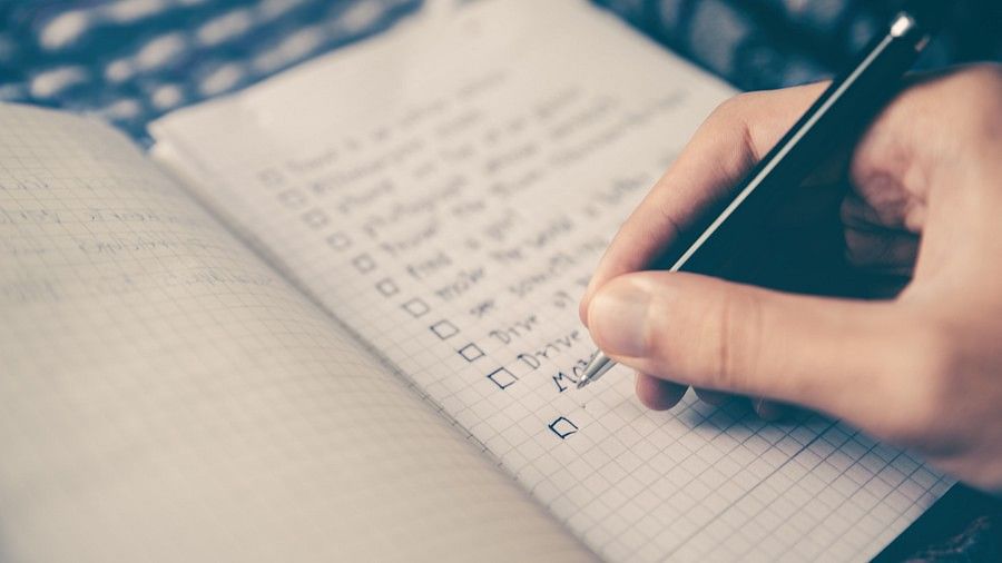 a close up image of a Person making a checklist on a book 