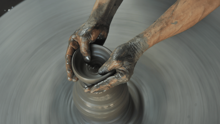 Close-up of a local artisan shaping raw clay into a pot on a spinning pottery wheel at Pottery Square in Bhaktapur, Nepal.