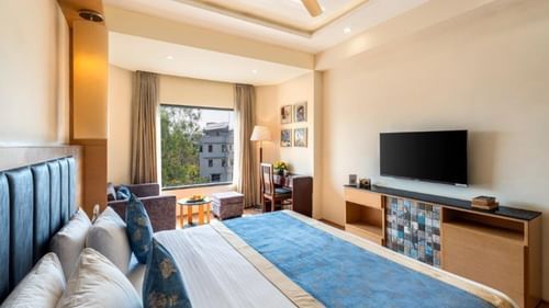 Superior Room with double bed, TV, couch, and balcony access at Golden Tulip, Udaipur.