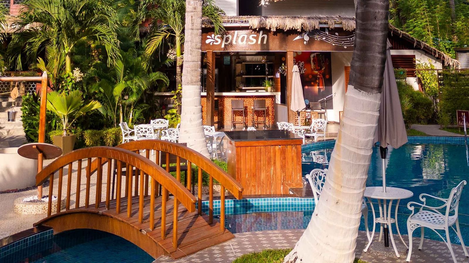 A view of a beautiful pool area with comfortable lounge chairs, palm trees, and a lush garden surrounding the pool. The atmosphere is calm and inviting, ideal for relaxation - Coral Reef Resort & Spa, Havelock