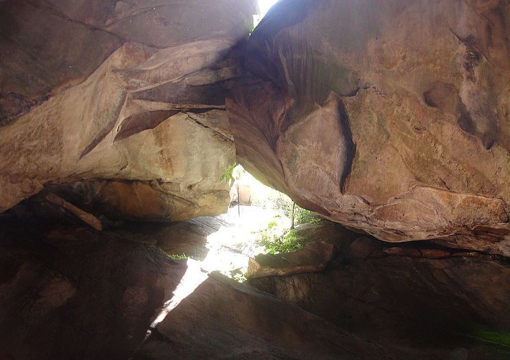 Inside view of an old cave, showing rough stone walls lit by sunlight coming through an opening