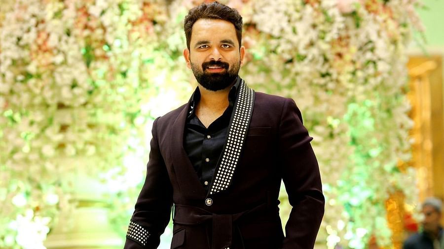 a man in black suit standing in front of a decorated background