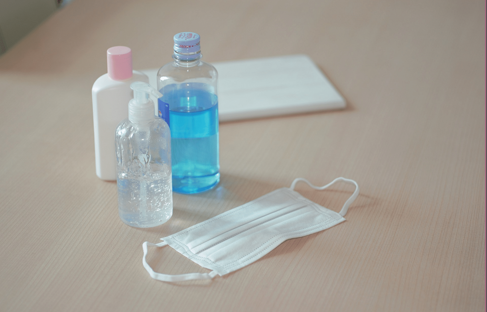 An image of sanitary products on the floor, including a face mask, towel, and sanitizers.