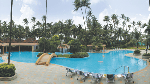 An overview of the Swimming Pool with a bridge and lounge chairs in view at The Retreat Hotel and Convention Centre Madh Island, Mumbai