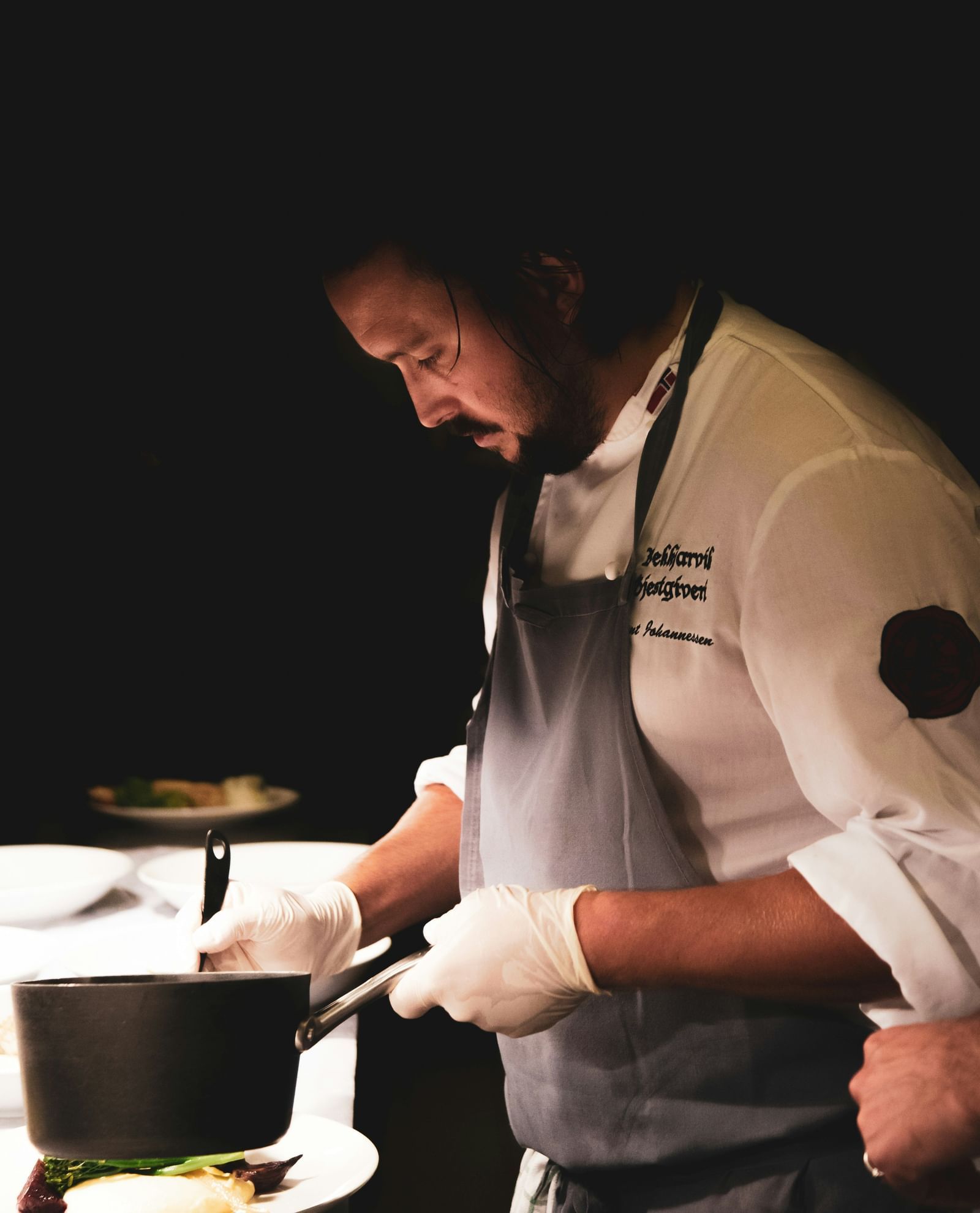 A chef with an apron cooking at his cooking station