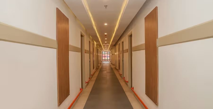 A well-lit hotel hallway with wooden panelling and a neat, minimalist design - Max Hotel Prayagraj.