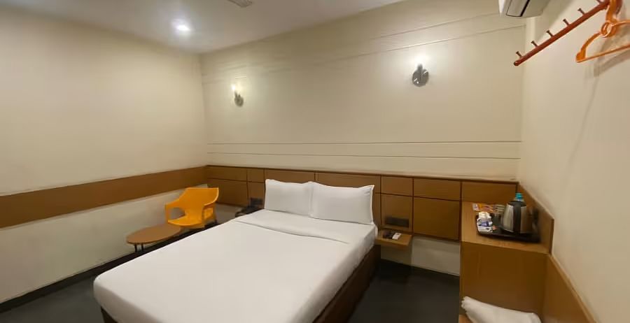 View of a hotel room with two single beds, a wooden table, and minimal decor - Max Hotel Prayagraj
