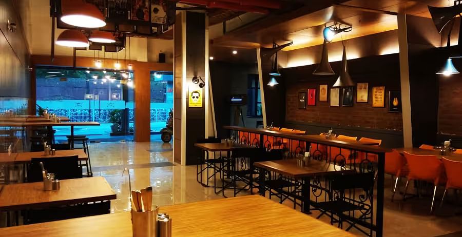 View of Mumbai Masala Restaurant with contemporary seating, warm decor, and large window - Max Hotel Prayagraj.