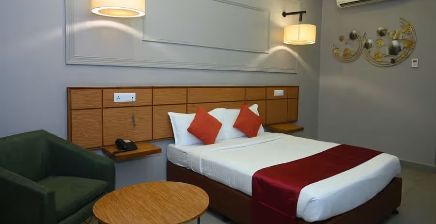 A well-designed hotel room with two beds, modern lighting, and a cosy seating area - Max Hotel Prayagraj.