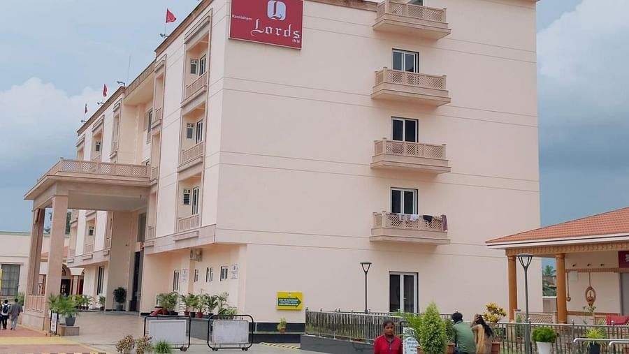 A multi-storey, light-pink building with multiple balconies is seen under a cloudy sky - Kankidham Lords Inn