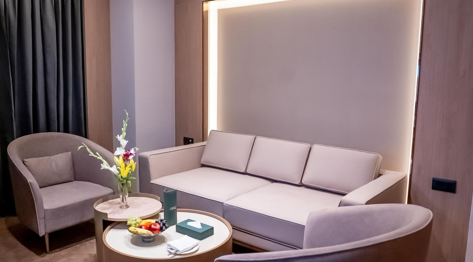 Living area with sofa, chairs and a window with a curtain in the background at ASTER GRAND BY ZENQ SAKET.