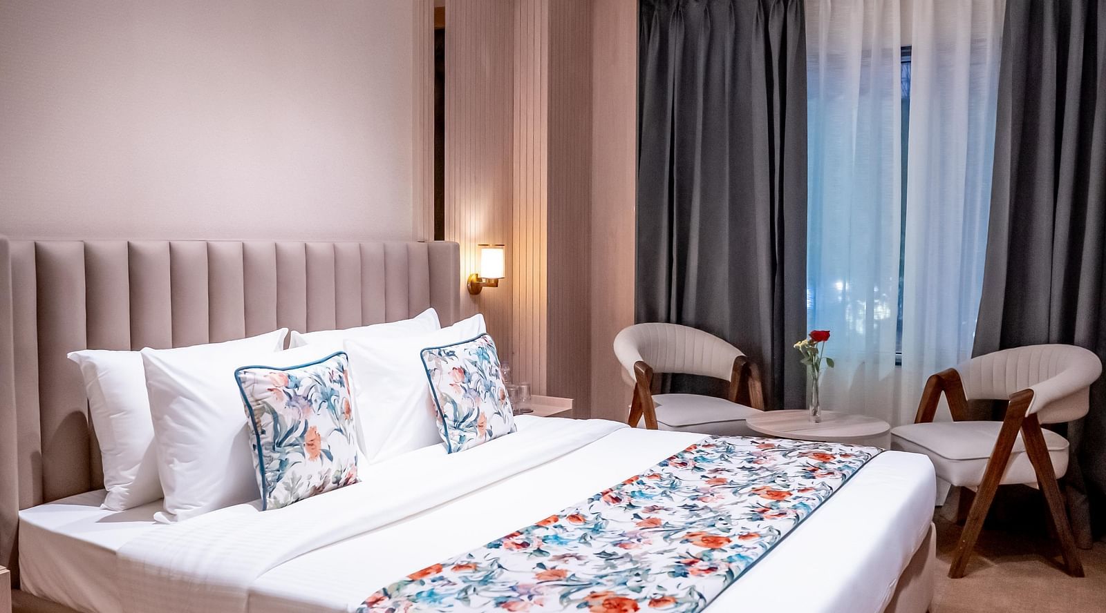 Bedroom with a queen size bed with chairs and window with a curtain in the background at ASTER GRAND BY ZENQ SAKET.