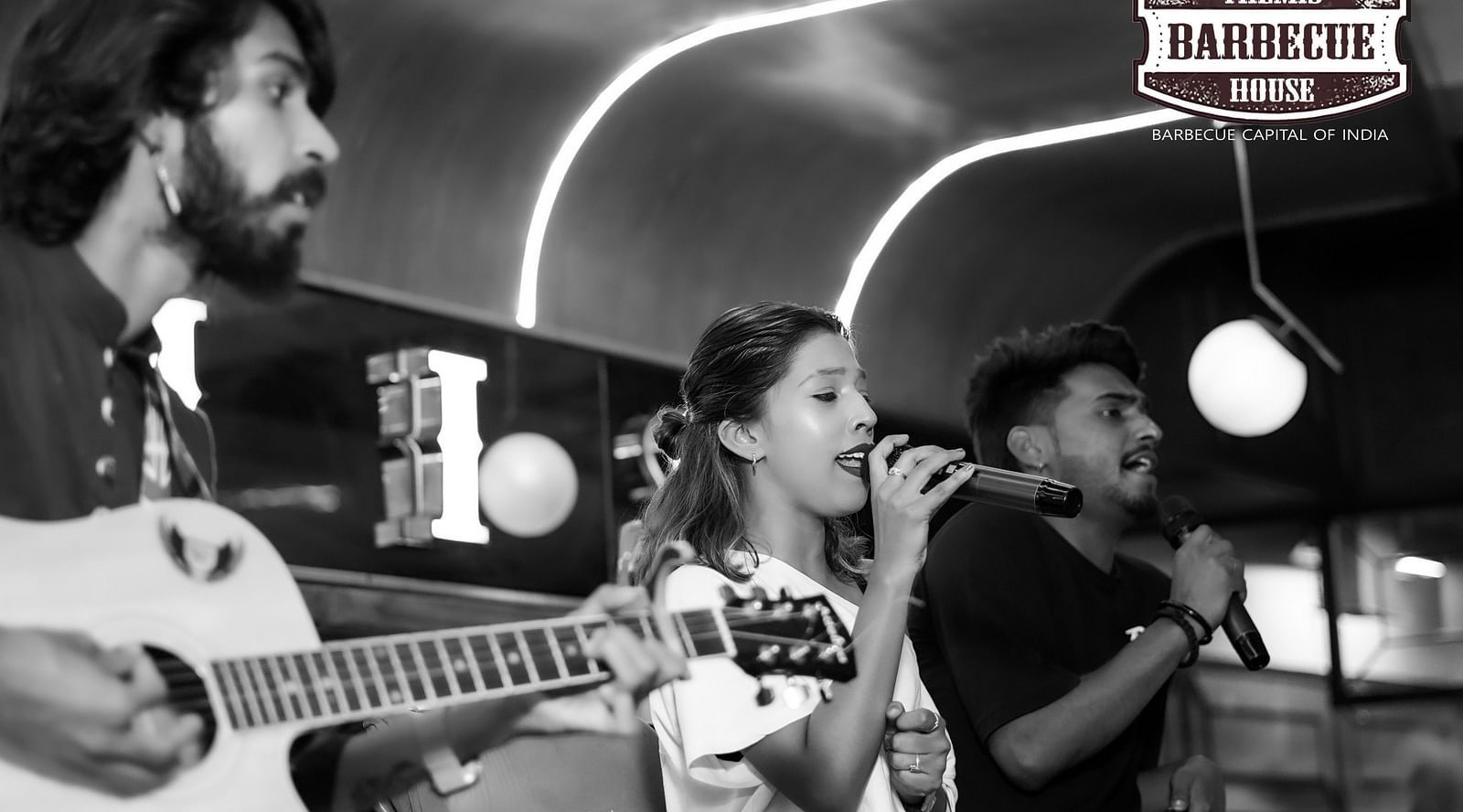 An image of two people singing on the stage while one person is playing a guitar - Themis Barbecue 