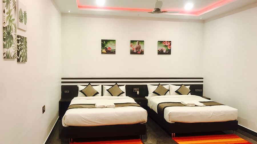 Image of a room with two beds and a ceiling fan above at  Parampara Residency, Kushalnagar..