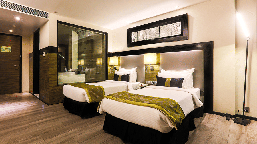 Twin Executive Room at The Empresa Hotel, Mumbai featuring two beds, and an attached bathroom with bathing tub.