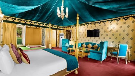 An overview of a tent with a double bed, sofas and a table seen - Rajasthali Resort & Spa, Jaipur.