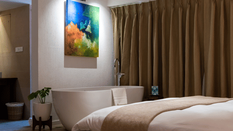 Large bed, bathtub, wall hanging and the washroom area at the Nepali Suite - The Nanee