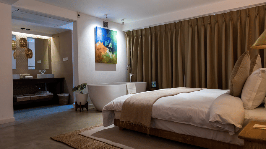 A spacious room with bed, bathtub, wall hanging and the washroom area at the Nepali Suite - The Nanee