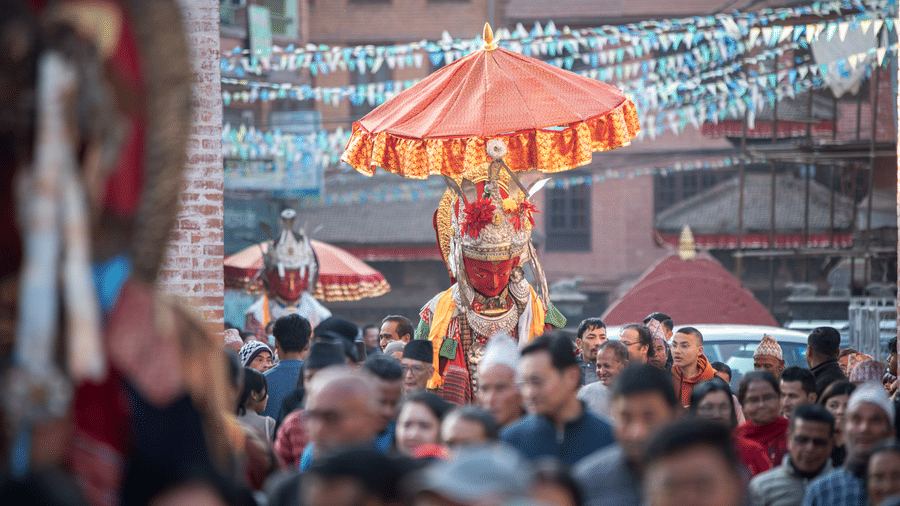 A vibrant street crowd accompanying a ceremonial umbrella and deity shrine during the Bisket Jatra festival in Bhaktapur, Nepal.