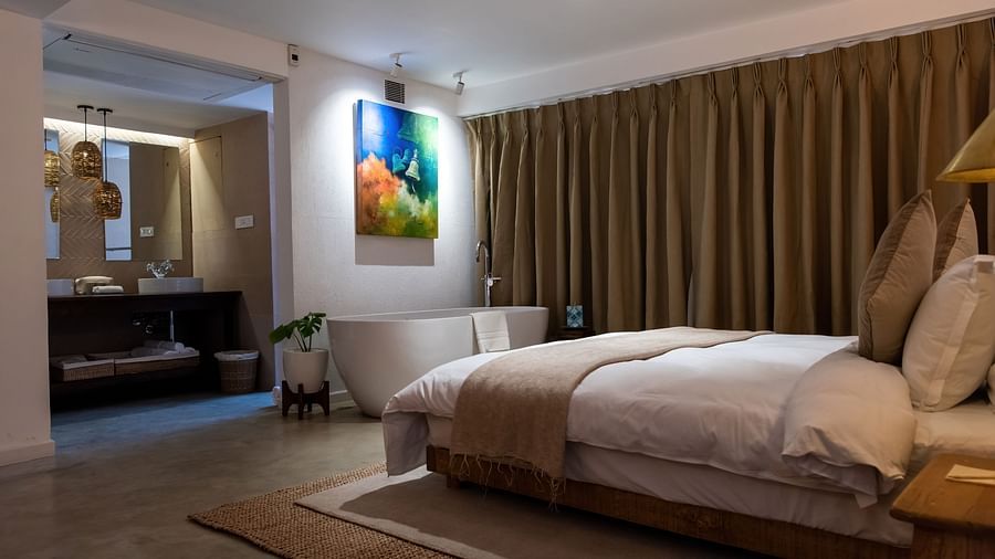 A spacious room with bed, bathtub, wall hanging and the washroom area at the Nepali Suite - The Nanee