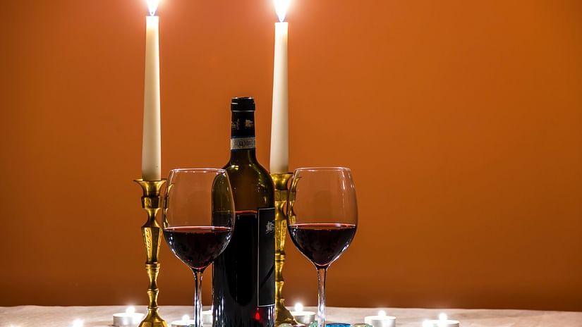 A table for two with candlelight, wine bottle and two glasses of wine already poured