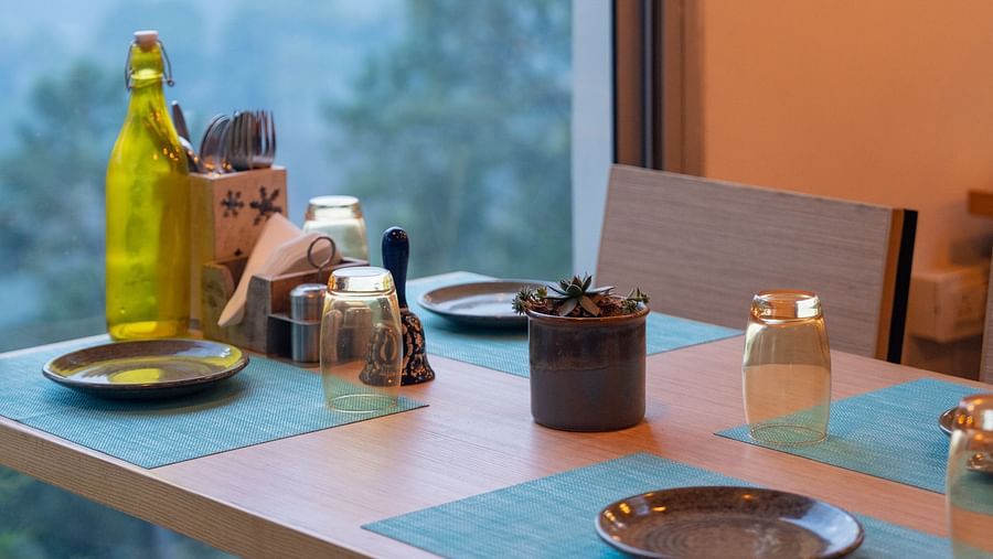 Restaurant table set with a glass bottle and plates at BluSalzz Escapade Resort, Lansdowne.