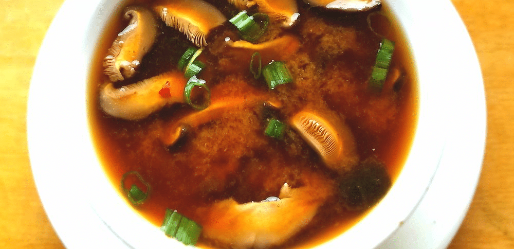A bowl filled with soup is viewed from above. 