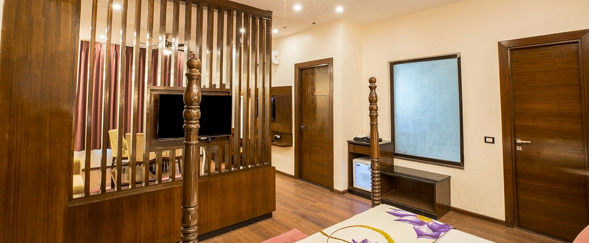 Corner view shot of the bedroom at the Suite with a wall mounted television on the wooden partition at Regenta Inn DLS.