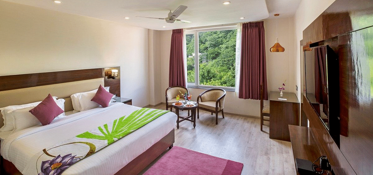 Full view shot of the Premium Room at Regenta Inn DLS featuring a double bed overlooking the lush green views from the window.