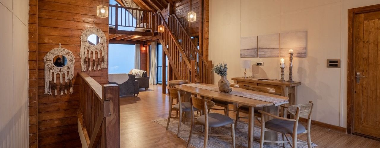 An image of dining space with table and chairs and stairs leading to the attic