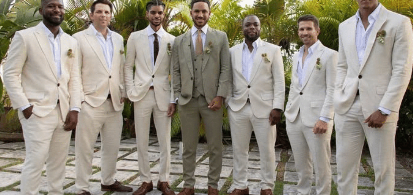 A group of groomsmen in beige suits standing outdoors on a stone pathway with greenery in the background | A Stone's Throw Away