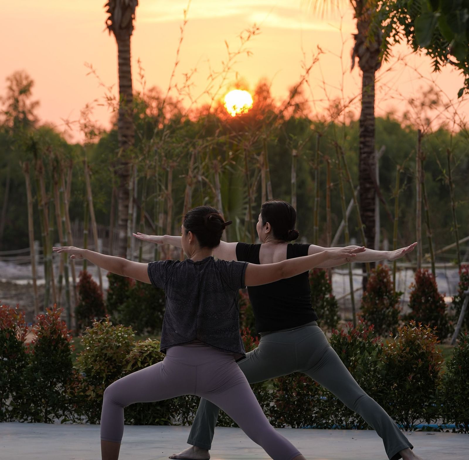 A yoga session at sunset at WoCAL Retreat Ke Ga with participants practicing mindfulness in a tranquil garden setting.
