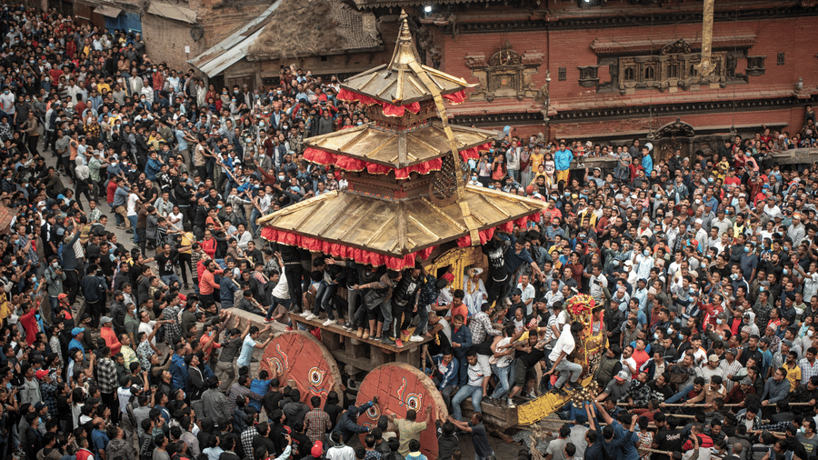 Overhead view of thousands of locals celebrating Bisket Jatra around a multi-tiered festival chariot in Bhaktapur Durbar Square, Nepal.