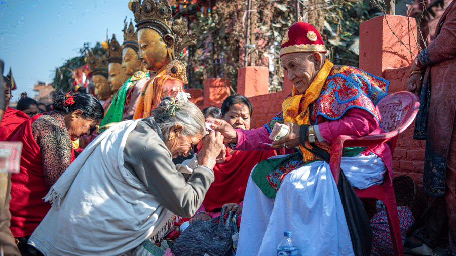 An elderly Newar woman giving a traditional blessing during the Tihar festival celebrations in a courtyard in Bhaktapur, Nepal.