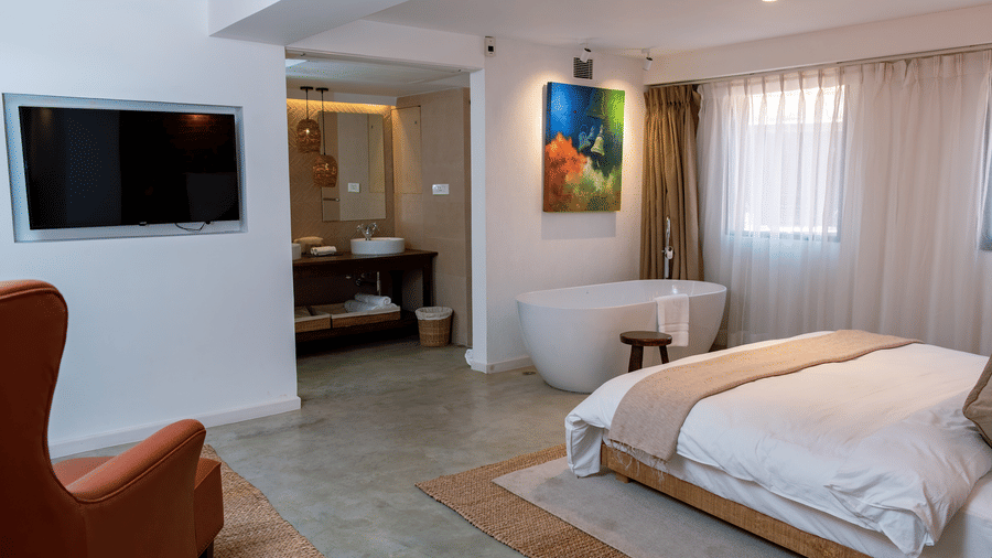 The Nepali Suite featuring a bed, flat screen TV, a sofa and a bathtub - The Nanee