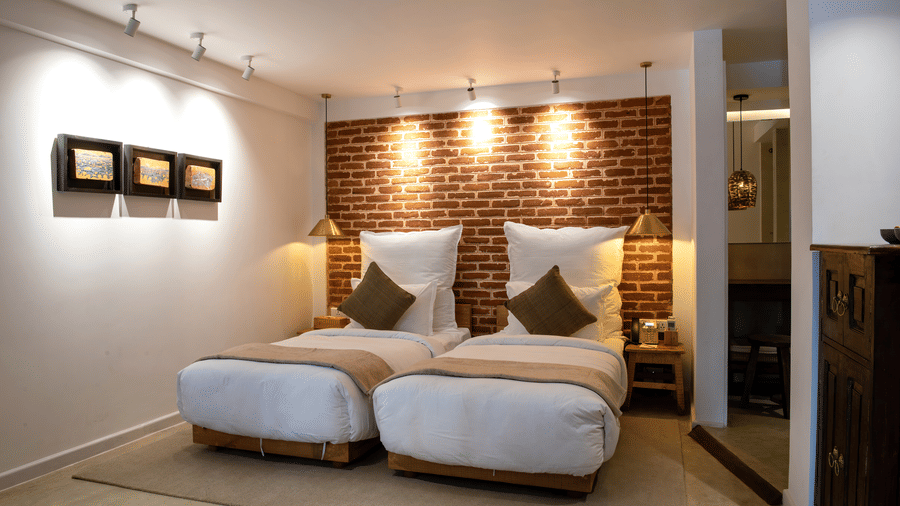 The room at The Nanee includes twin beds, bedside tables with lamps, and three pieces of artwork displayed on the wall.
