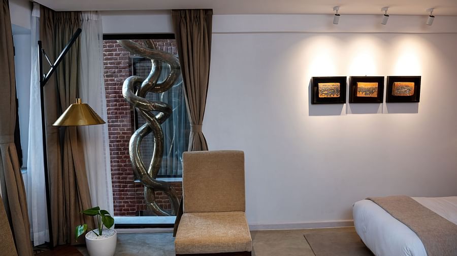 A room with a bed, chair, lamp, three pieces of art work hung on the wall, and a window overlooking the infinity loop - The Nanee