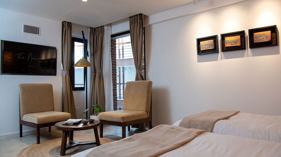 A room with a bed, chairs, table, flat screen TV, and three artwork hung on the wall - The Nanee
