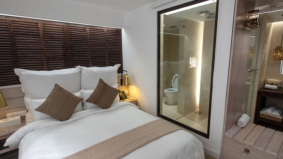 Standard room with a bed, bed side table, lamps and the washroom area - The Nanee