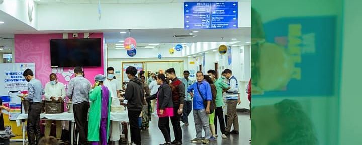 Volunteers at HCG Hospital serving meals to patients and visitors as part of the Annakshetra initiative, with people standing in line and receiving food in a clean, organised setting.