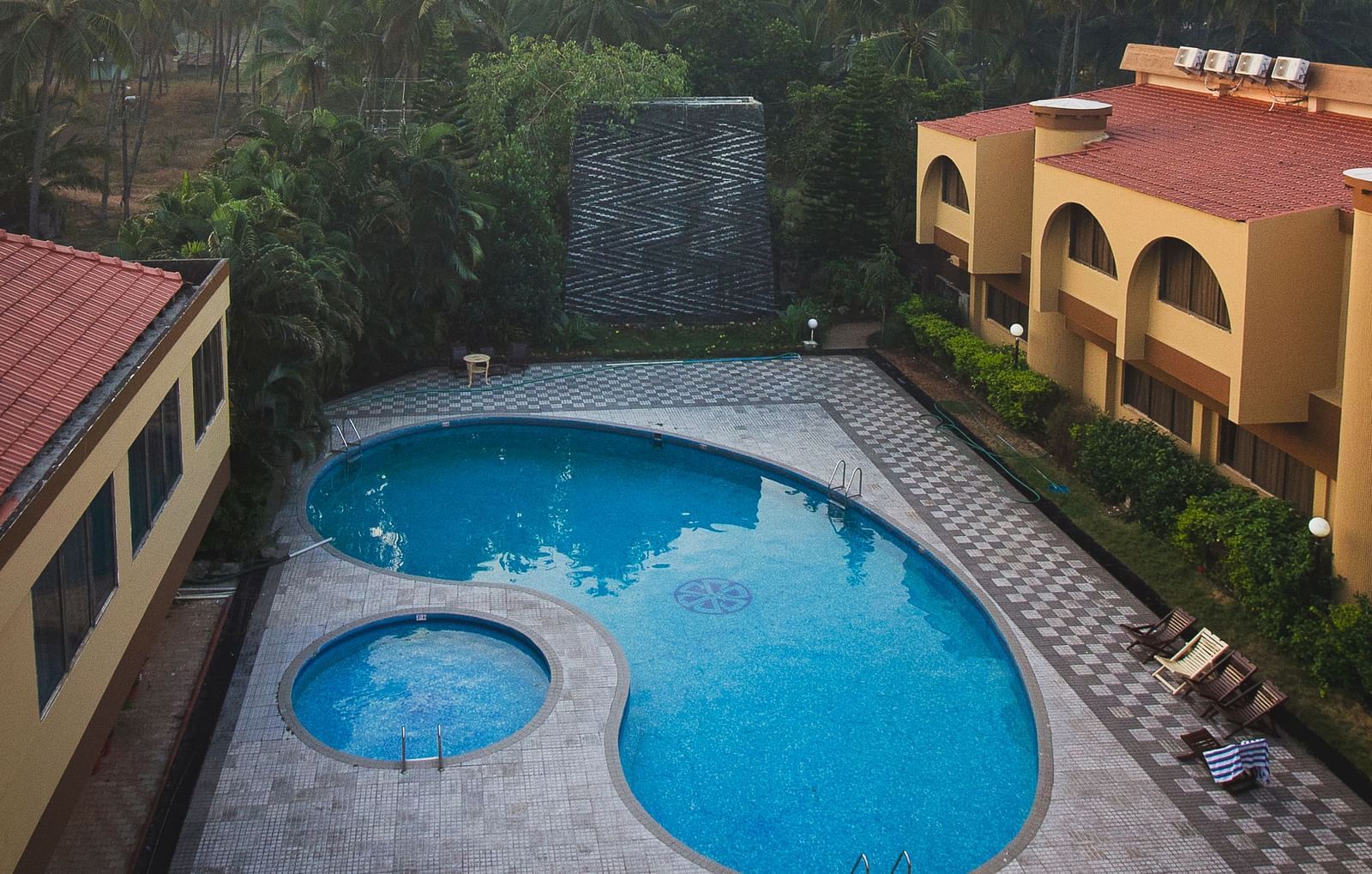 Aerial view of the swimming pools at Paradise Isle Beach Resort, Udupi with the resort in the backdrop