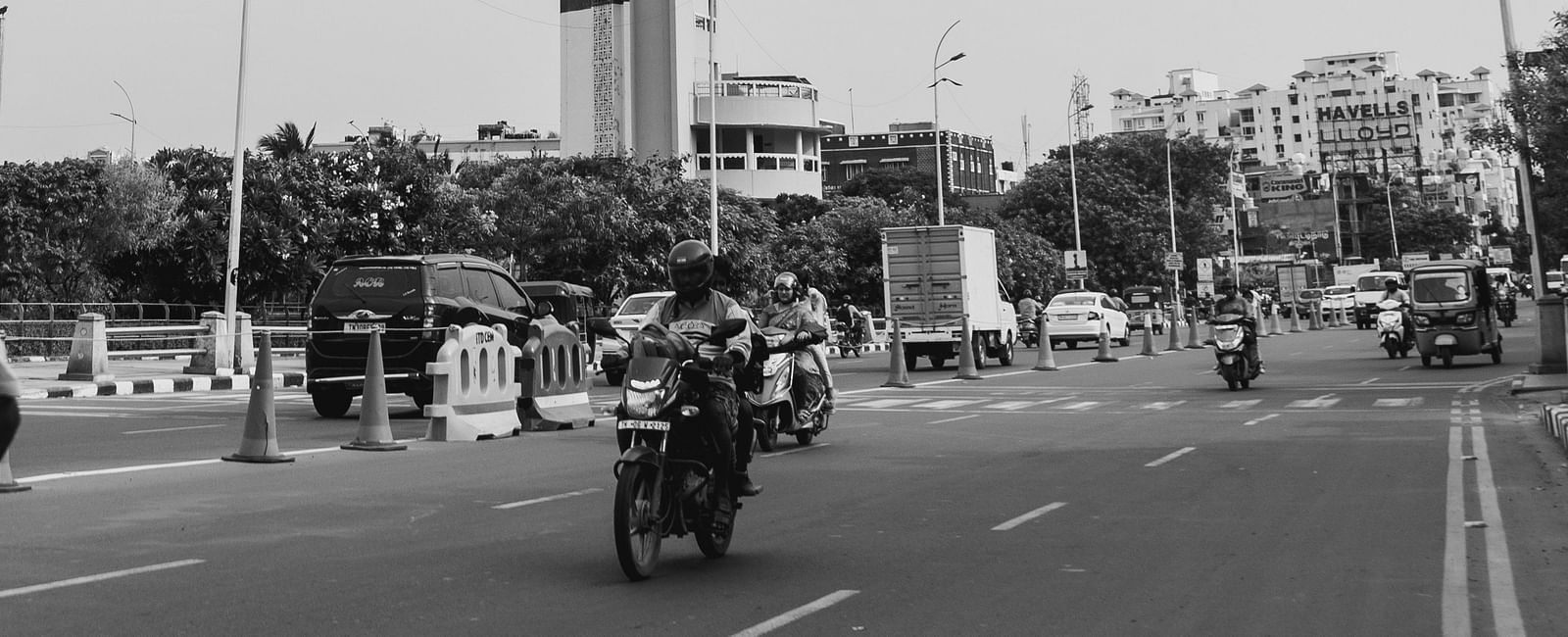 An overview of a light house in Chennai with bikes riding on the road next to it.