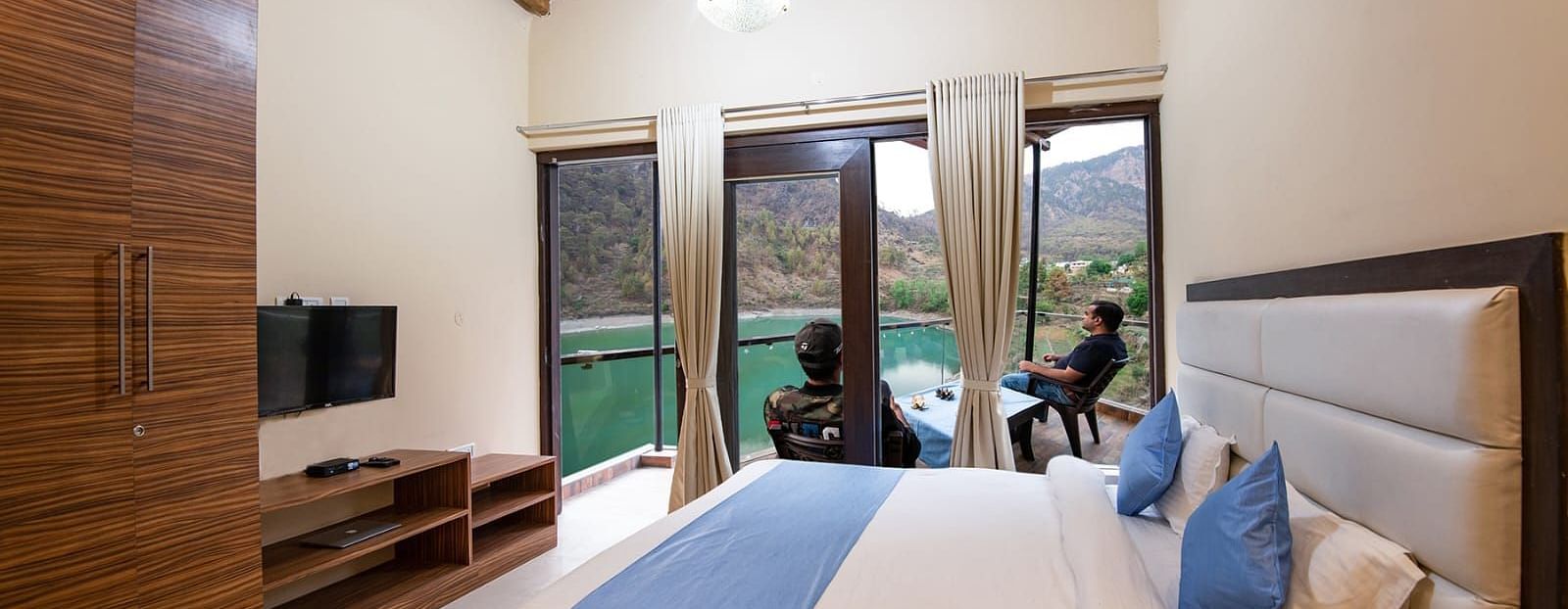 Double bed facing a flat-screen TV and glass doors opening to a balcony 