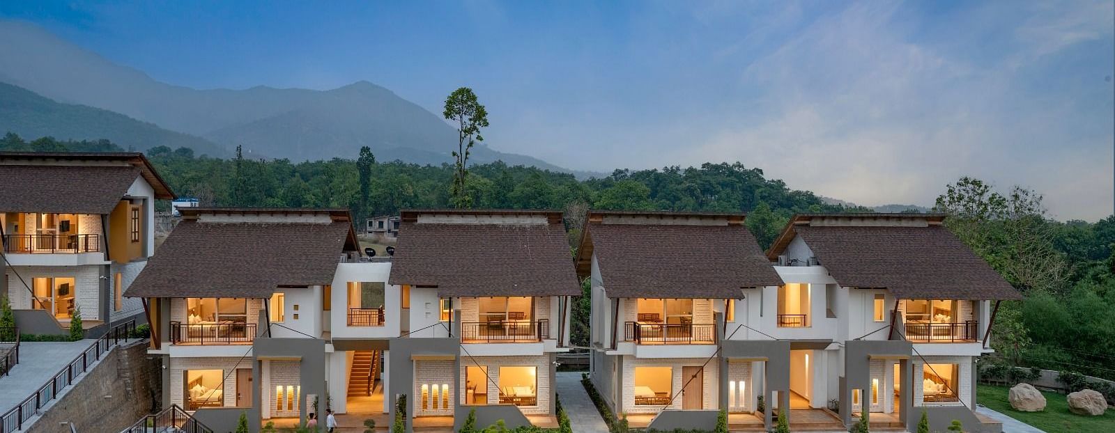 A resort nestled amidst rolling hills, featuring a swimming pool, lush greenery, and several buildings.