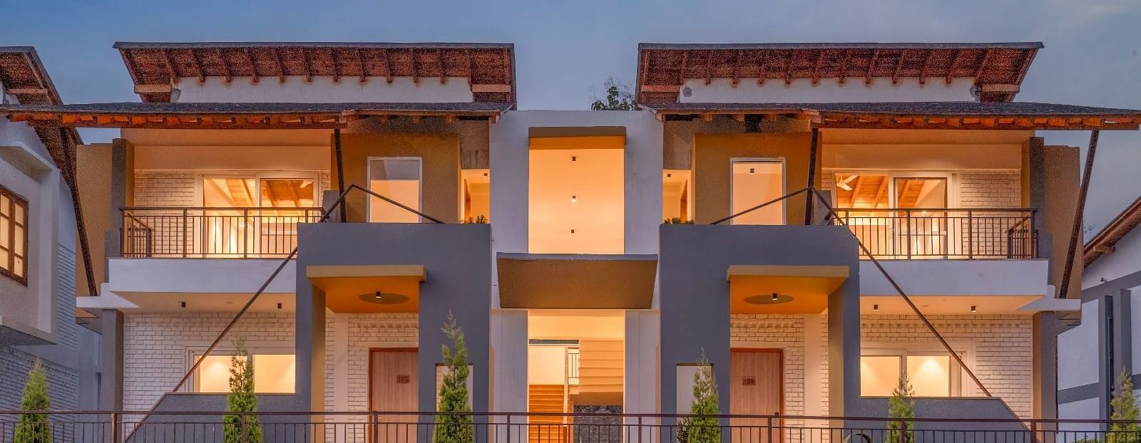 A row of modern houses with balconies, lit up at night.