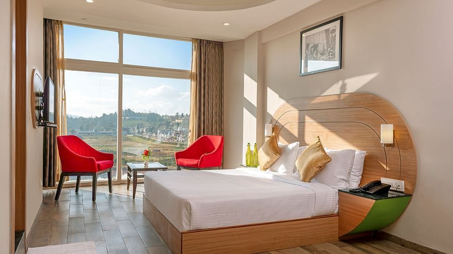 An image of a bedoom where natural light is seeping in through the glass window | Mango HIll Central, Ooty